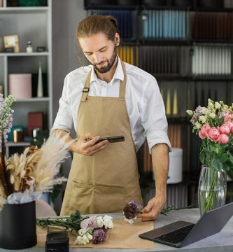 florists-making-bouquet-of-flowers-on-counter-and-taking-photo-on-smartphone-for-social-media