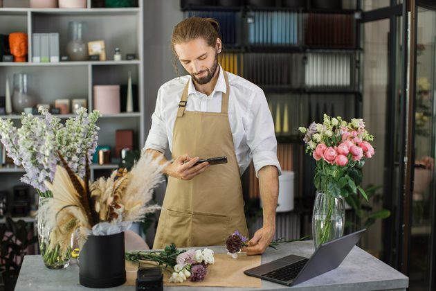florists-making-bouquet-of-flowers-on-counter-and-taking-photo-on-smartphone-for-social-media